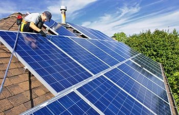 Man installing alternative energy photovoltaic solar panels on roof