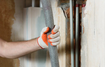 Workers hand is holding insulation for home heating pipes
